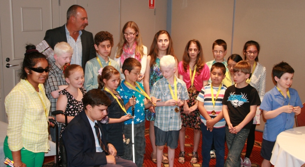 Andrew Daddo with a group of blind children holding medals