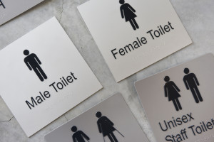 Toilet signs with braille and raised text and graphics. 