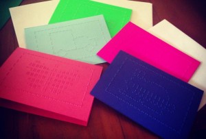 Greeting cards made from green, blue or pink cardstock with an outline and picture on the front made with braille dots