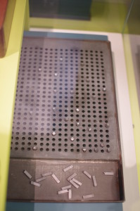 A Taylor slate, a metal plate with grid of holes and rods.